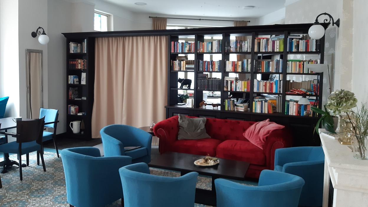 Wohnbereich mit Bücherregal Gemütlicher Wohnbereich mit rotem Sofa, blauen Sesseln und großer dunkler Bücherwand.