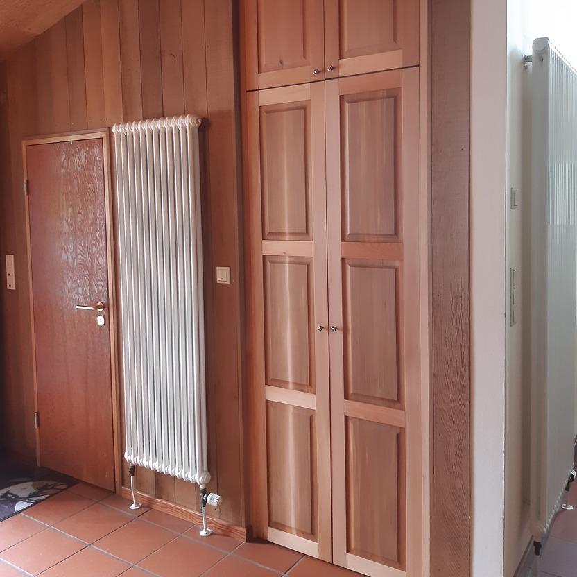 Holzschrank im Dachgeschoss Hoher Holzschrank mit Kassettentüren ist in eine Wandnische im Dachgeschoss eingebaut.