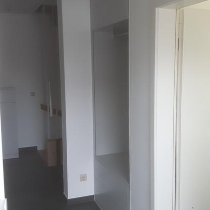 Einbauschrank im Eingangsbereich Hoher weißer Einbauschrank mit Sitzbank und Ablagefläche nutzt den Flurbereich platzsparend aus.