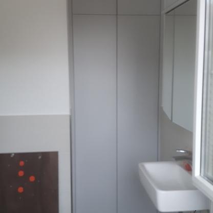 Hochschrank im Badezimmer Schmaler grauer Hochschrank steht passgenau neben Waschbecken und Spiegel in einem hellen Bad.