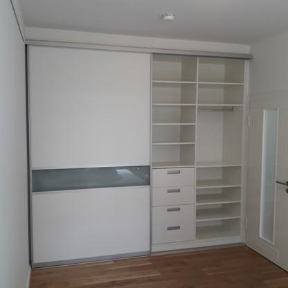 Kleiderschrank mit Schiebetüren Weißer Kleiderschrank mit Schiebetüren, Glasfeld, offenen Fächern und Schubladen im Schlafzimmer.