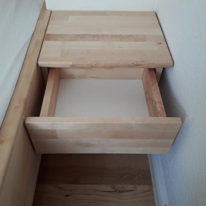 Holzschublade neben dem Bett Offene Holzschublade mit passender Ablagefläche ist platzsparend neben einem Bett eingebaut.