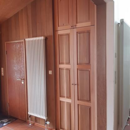 Holzschrank im Dachgeschoss Hoher Holzschrank mit Kassettentüren ist in eine Wandnische im Dachgeschoss eingebaut.