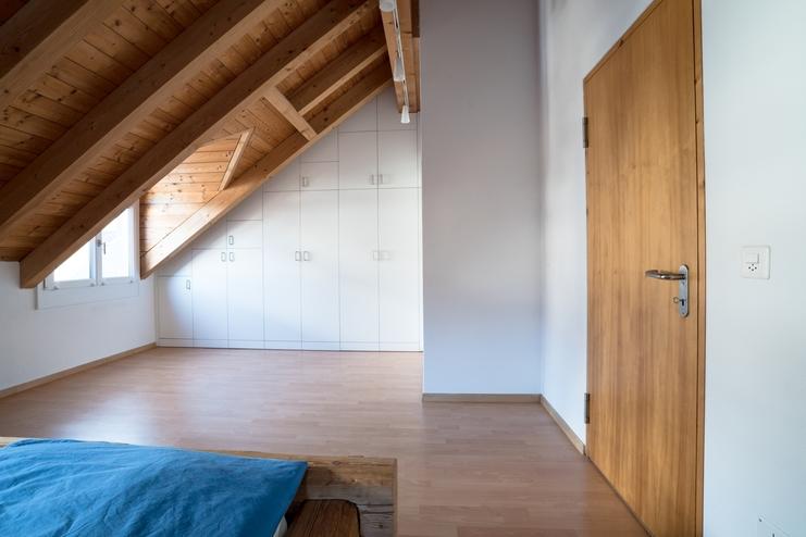 Nischenlösung für Einbauschrank an holzbelassener Dachschräge Nischenlösung für weißen Einbauschrank mit Schubladen und Türen an in dunklem Holz belassener Dachschräge