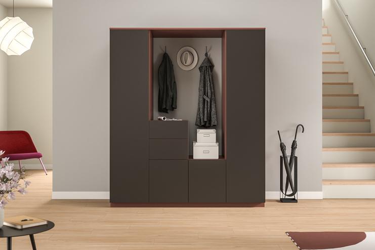 Maßgefertigter Garderobenschrank im stilvollen Eingangsbereich. Ein dunkler, maßgeschneiderter Schrank mit integrierter Garderobe und Schubladen, praktisch für die Aufbewahrung von Jacken und Accessoires im Eingangsbereich.