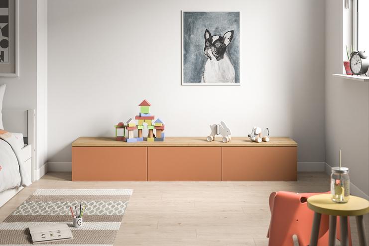 Farbige Kommode nach Maß in einem lebhaften Kinderzimmer. Eine moderne, terrakottafarbene Kommode nach Maß bietet mit ihrer glatten Oberfläche und geräumigen Schubladen einen kindgerechten Stauraum im Zimmer.