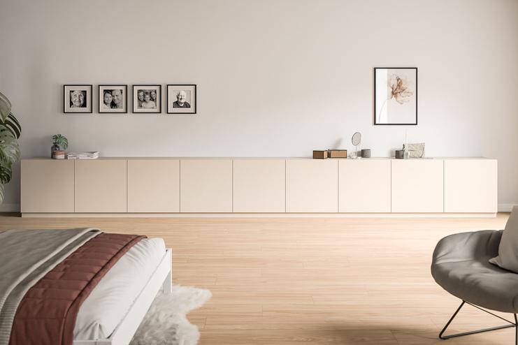 Langes, cremefarbenes Sideboard nach Maß in einem hellen Zimmer Niedriges, maßgefertigtes Sideboard in Creme, unter einer Wandgalerie aus Familienfotos, ergänzt durch minimalistische Dekoration.
