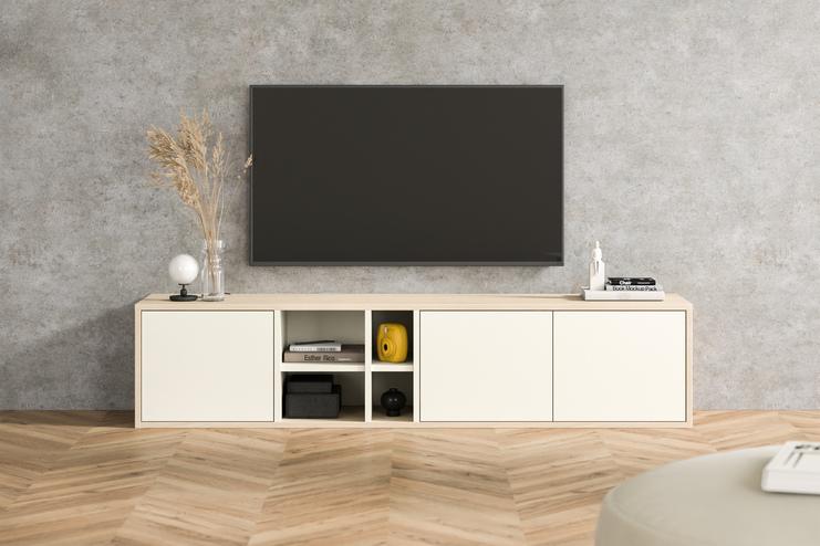 Moderne Kommode nach Maß unter TV im Wohnzimmer Maßgefertigte Kommode in Creme mit offenen Fächern und gelben Akzenten, unter einem Wandfernseher, vor einer Betonwand im urbanen Wohnzimmer.